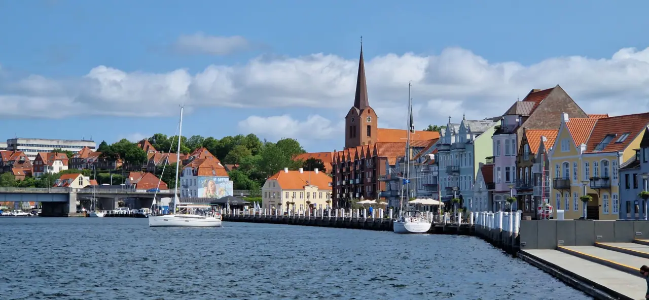 Hafenstadt mit Kirchturm und Giebelhäusern am Wasser